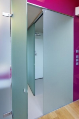 Matné sklo dveří kontrastuje s vysokým leskem desek, kterými je koupelna obložena